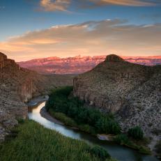 Beyond the natural hot springs of Boquillas Canyon in Big Bend National Park, Texas, the Rio Grande River snakes along the cliffs along the trail to Rio Grande Village. The Rio Grande is a natural border separating Mexico (on the right) from the United States (left). In the distance the Sierra Del Carmen Mountains are visible. During the day, the desert looks almost monochromatic, with neutral tones domination, but as the sun sets, colors and contrast begin to pop, with a range of pastels bouncing off every surface. It's also a lot cooler, which makes longer hikes much easier.