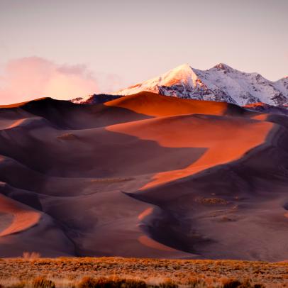 Sand dunes and mountain peaks lit with evening light. Great Sand Dune National Park, Alamosa, Colorado.