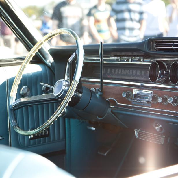 1018915066 A photograph of an American Classic car, as seen through the side window, showing the steering wheel, dash board and blue interior, Image taken in August 2018 on a sunny day at Goodwood Motor Circuit, in the UK, at a classic car meeting (breakfast club), open to the general public.