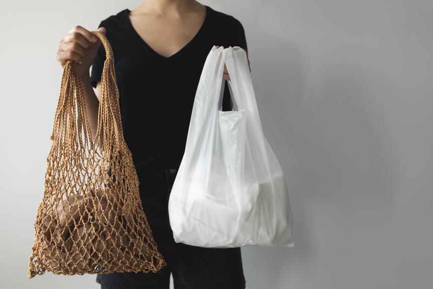 1208044927 Woman holding mesh eco bag shopper and plastic shopping bags. What you choose: plastic bags or multi-use eco bags. Zero waste concept with copy space.