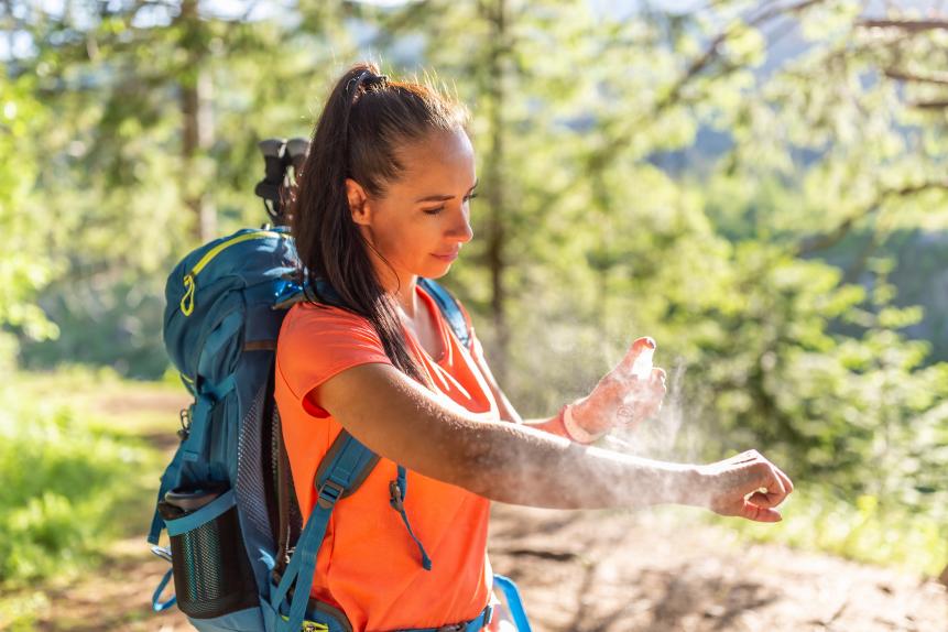 1404334863 A woman applies mosquito spray to her hands during hiking.